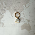 Dog tag shaped as a cupcake on a world map background.