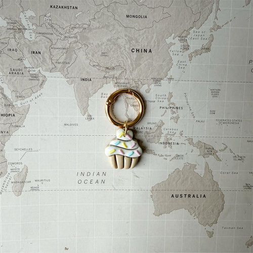 Dog tag shaped as a cupcake on a world map background.