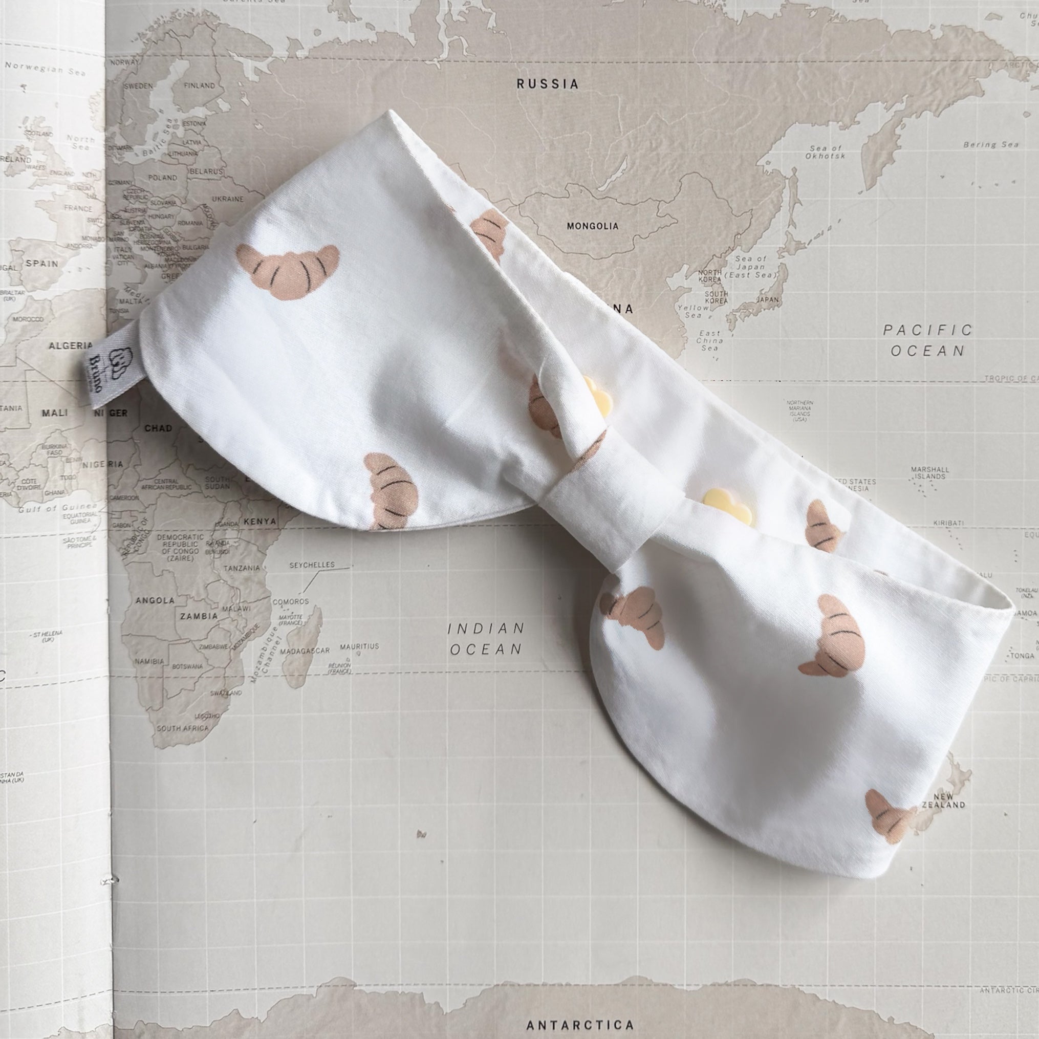 White bowdana with brown croissants on a world map background.