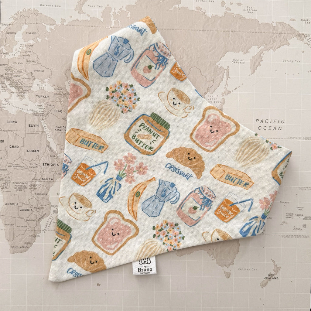 Dog bandana with breakfast related motifs on a world map background.