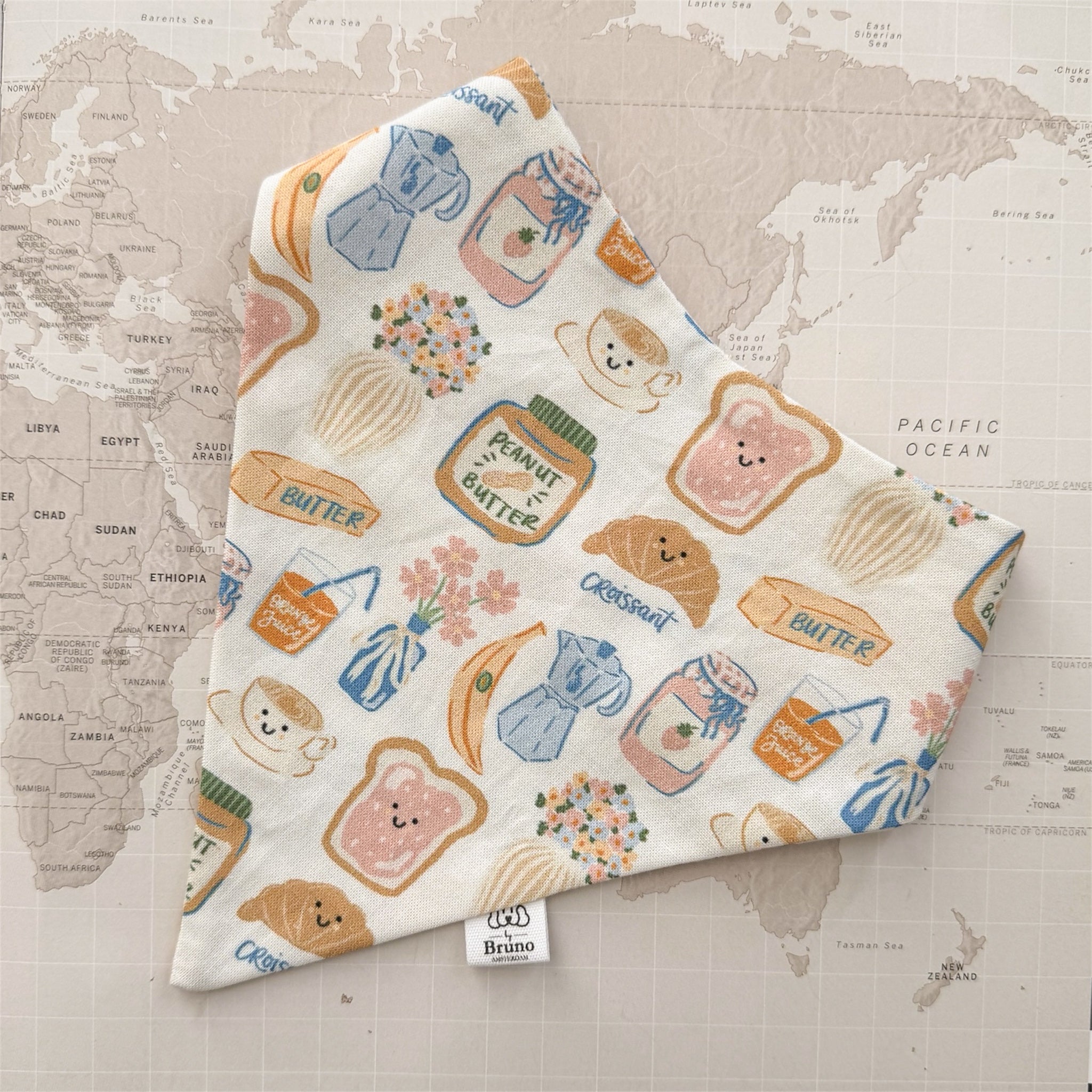 Dog bandana with breakfast related motifs on a world map background.
