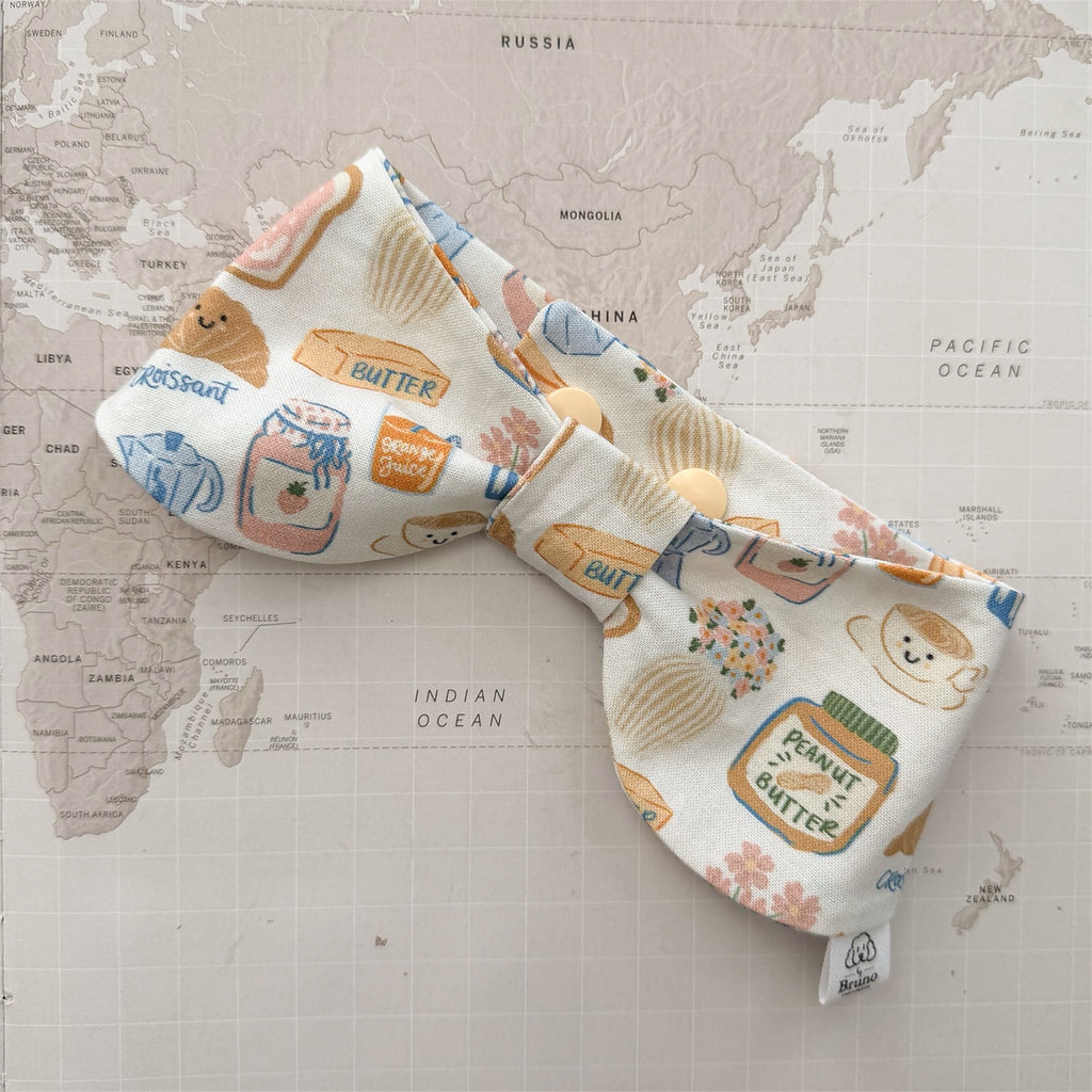 Dog bow bandana with breakfast-themed motifs on a world map background.