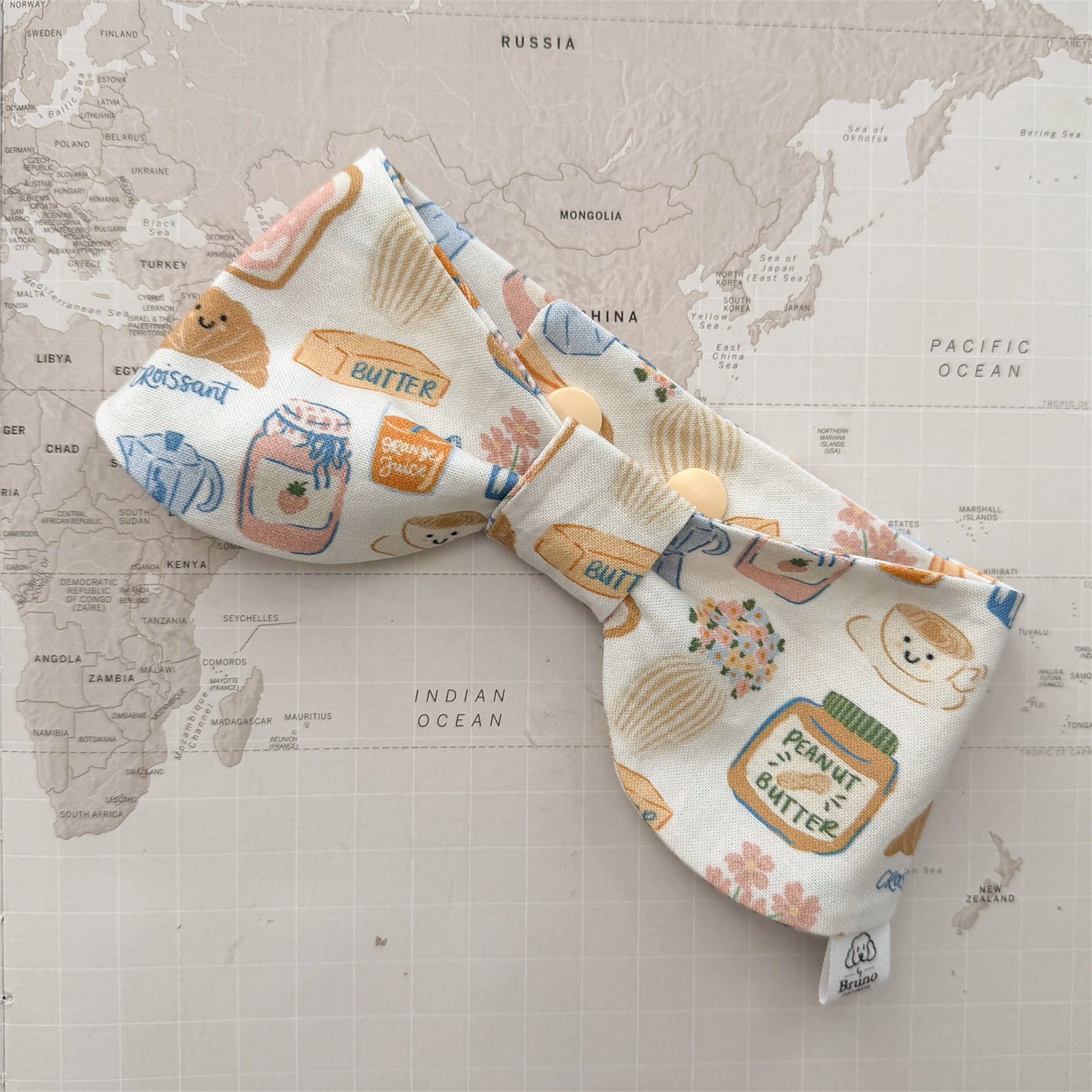 Dog bow bandana with breakfast-themed motifs on a world map background.