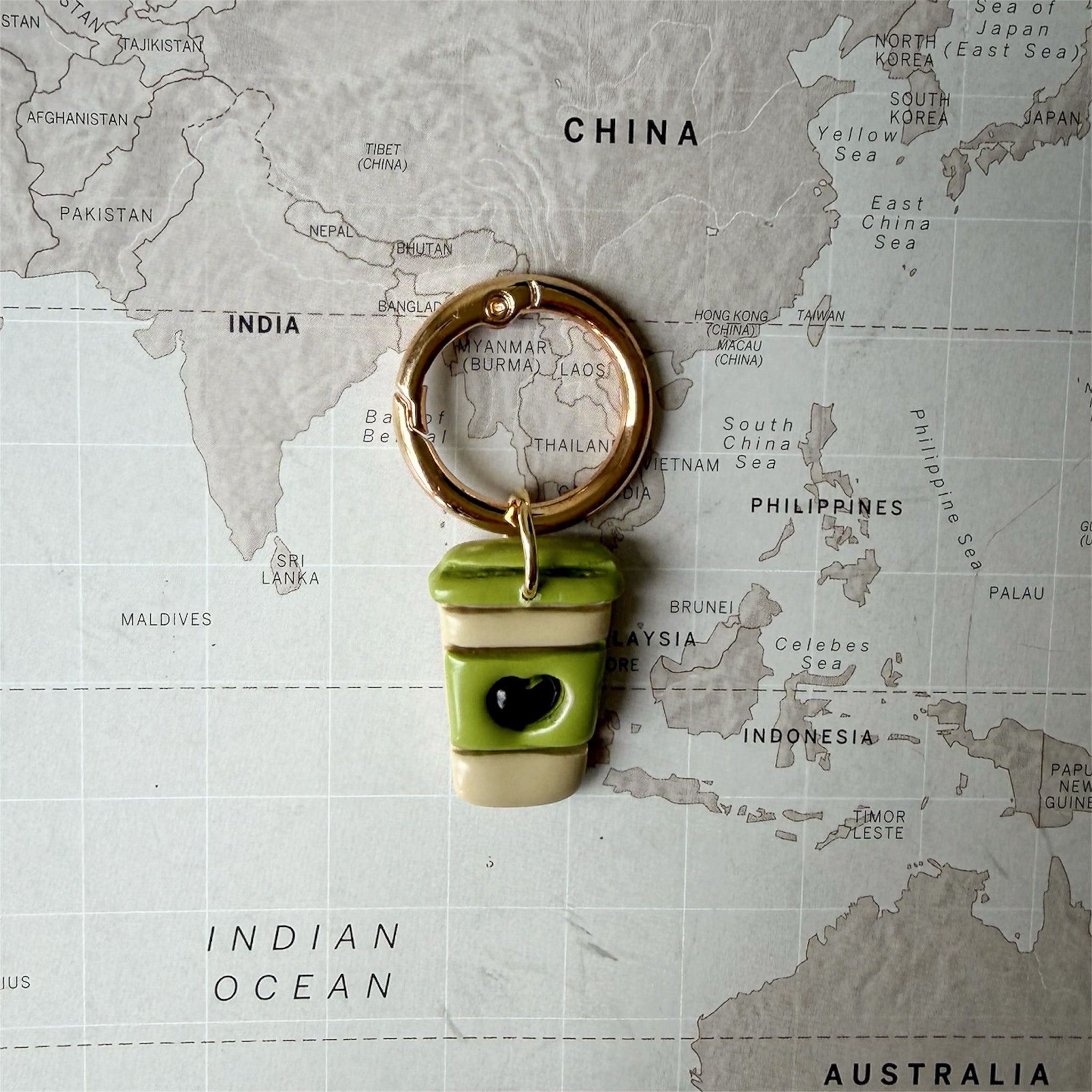 Green coffee cup dog tag with a heart on a world map background.
