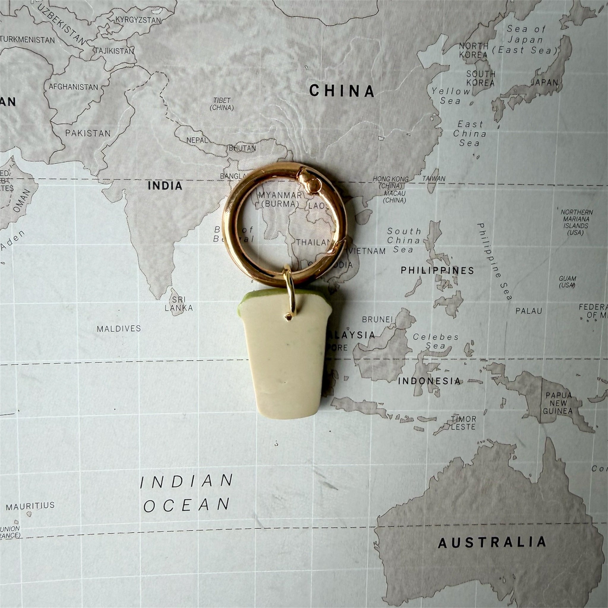 Back side of the green coffee cup dog tag with a heart on a world map background.
