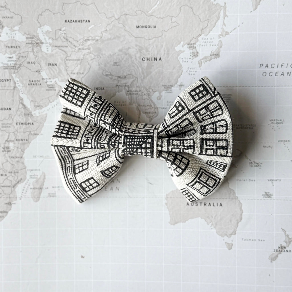 A dog bow with Amsterdam Canal Houses print on a world map background.