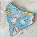 A blue dog bandana with multicolored poodles on a world map background.