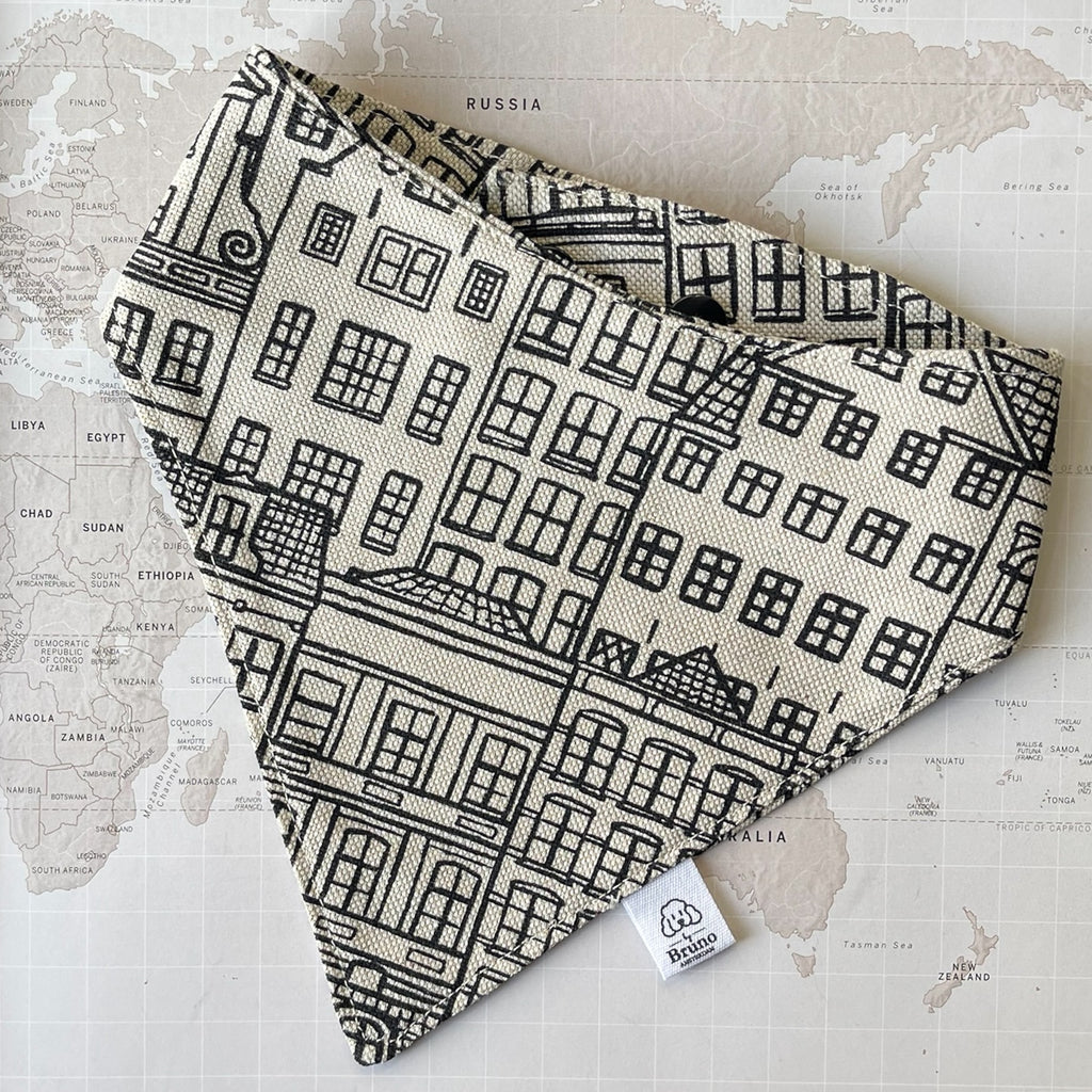 A dog bandana with Amsterdam Canal Houses print on a world map background.