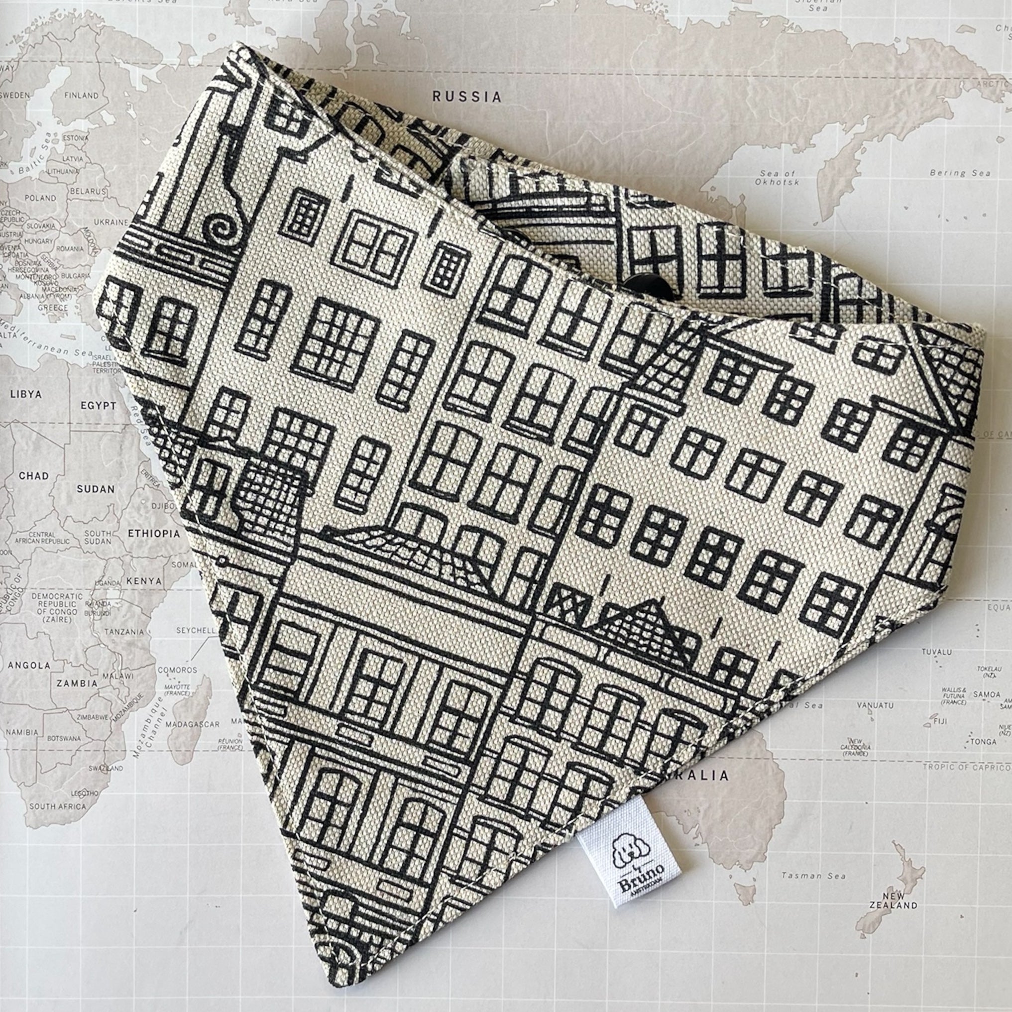 A dog bandana with Amsterdam Canal Houses print on a world map background.
