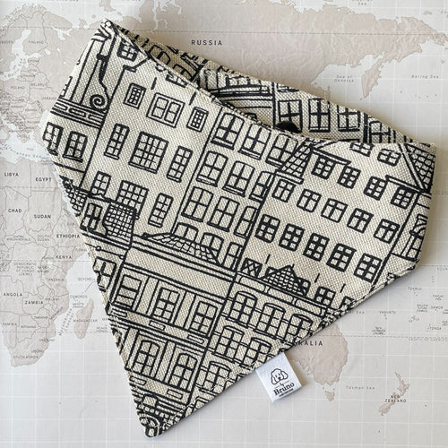 A dog bandana with Amsterdam Canal Houses print on a world map background.