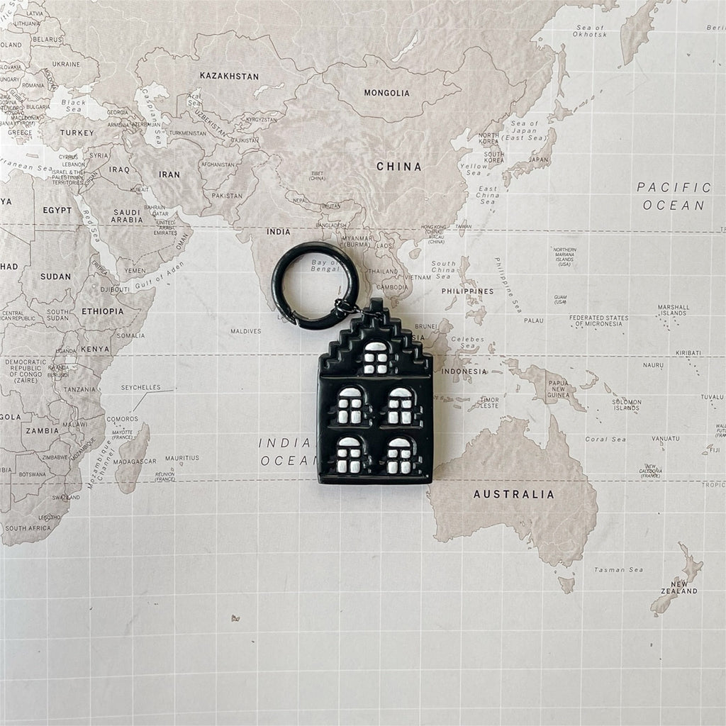 Amsterdam house shaped dog tag on a world map surface.