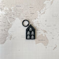 Amsterdam house shaped dog tag on a world map surface.
