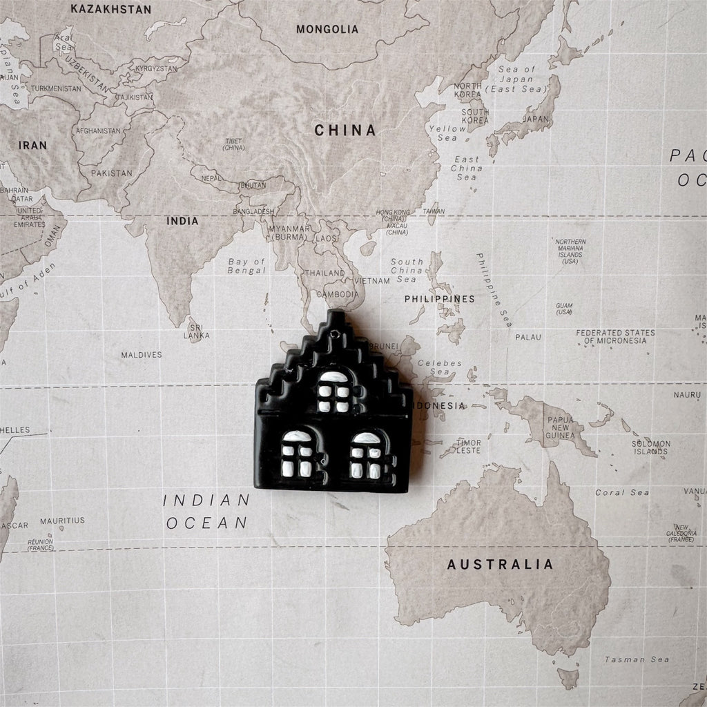 Amsterdam house shaped dog tag on a world map surface.