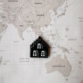 Amsterdam house shaped dog tag on a world map surface.