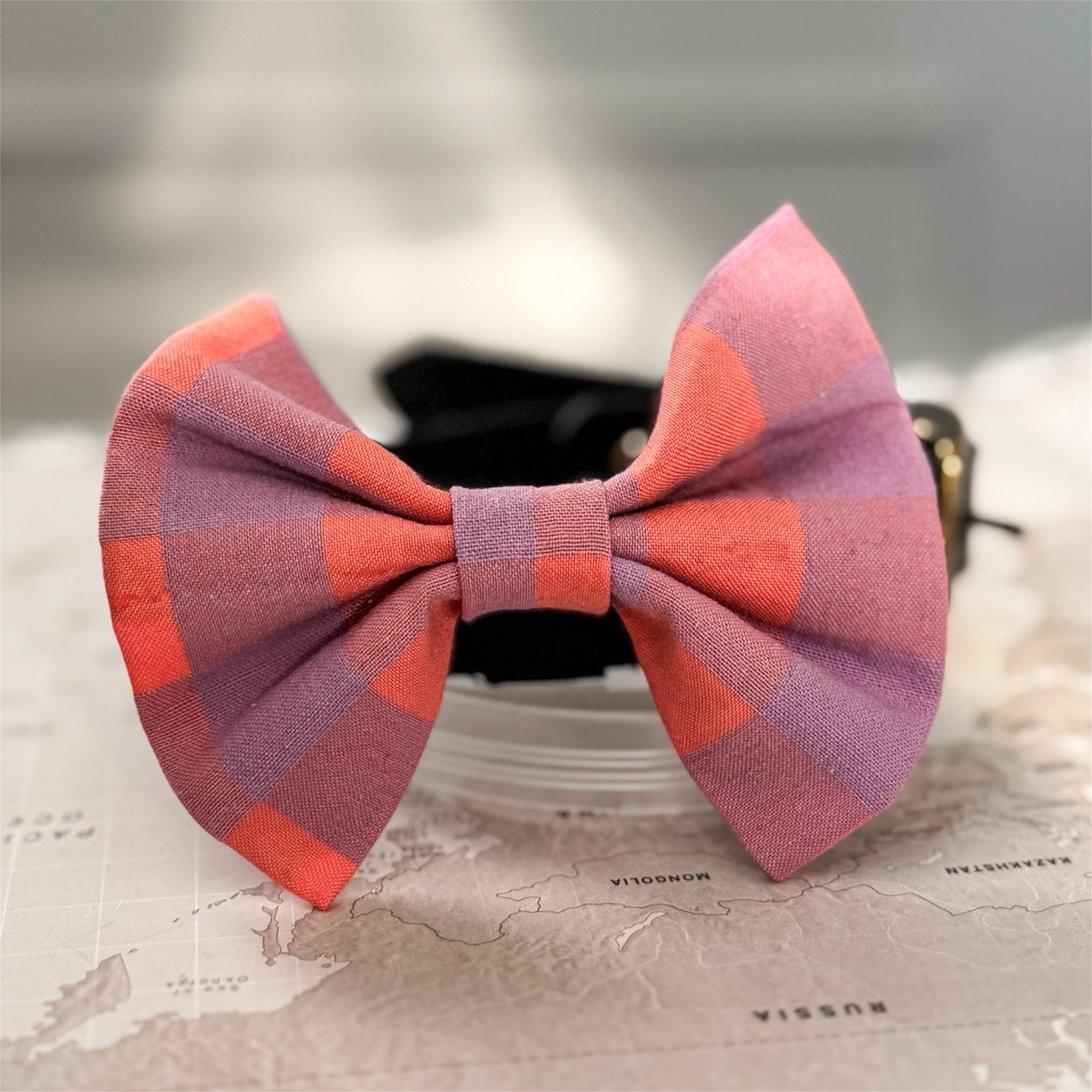 Plaid bow tie on a textured surface with a blurred background
