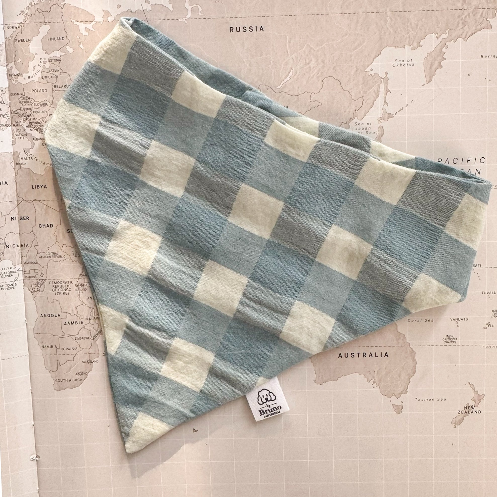 Blue and beige checkered fabric with a brand label on a world map background.