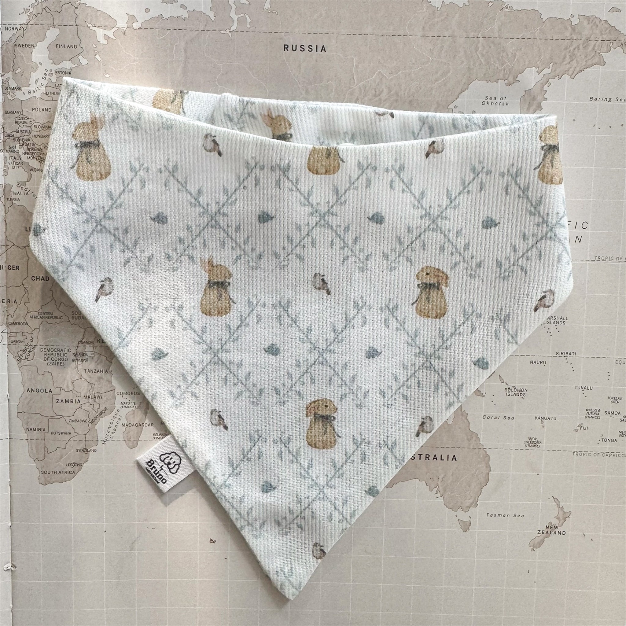 Easter dog bandana with bunnies and birds on a world map background.