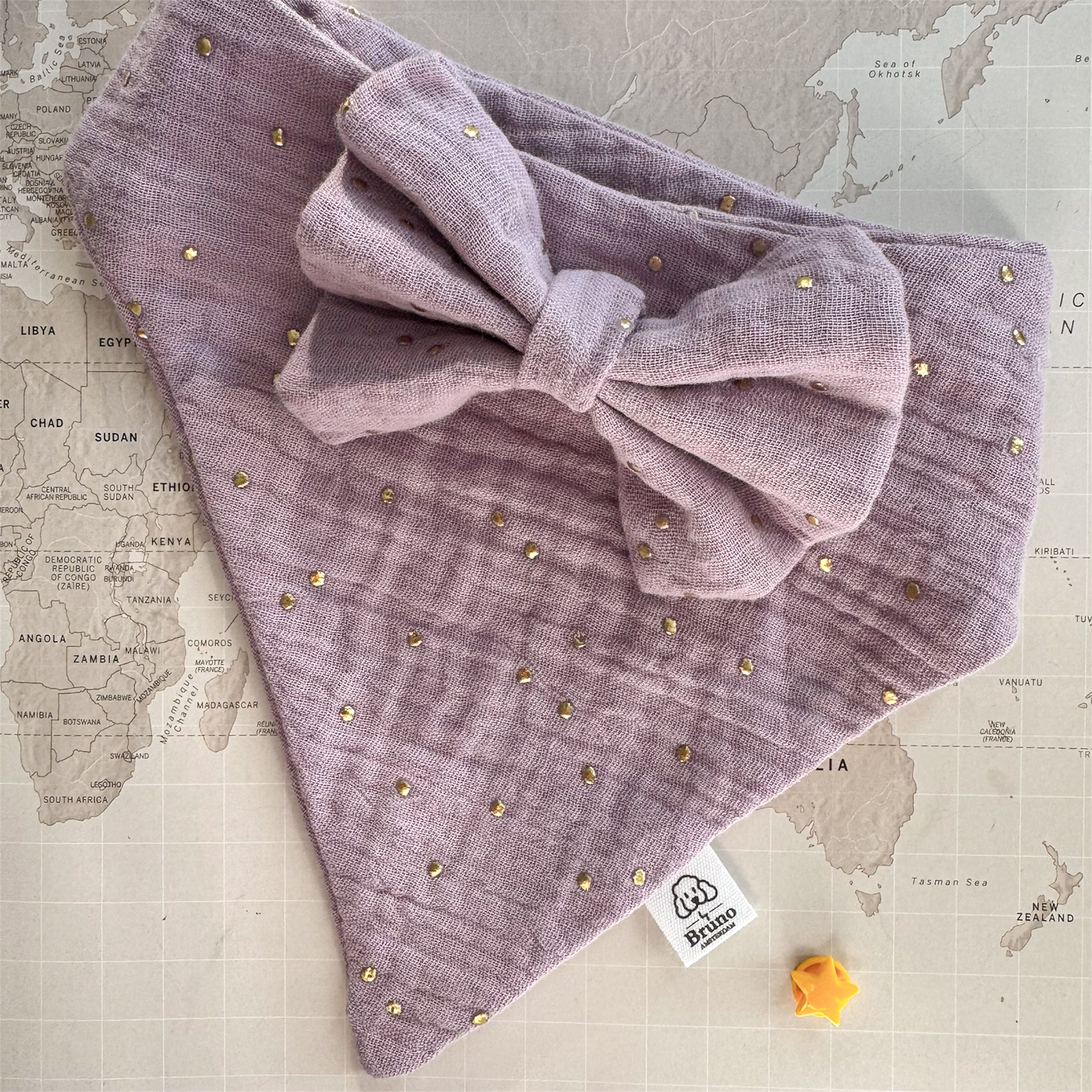 Purple dog bandana with gold studs on a map background.

