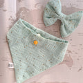Mint dog bandana with golden studs and a bow on a world map background

