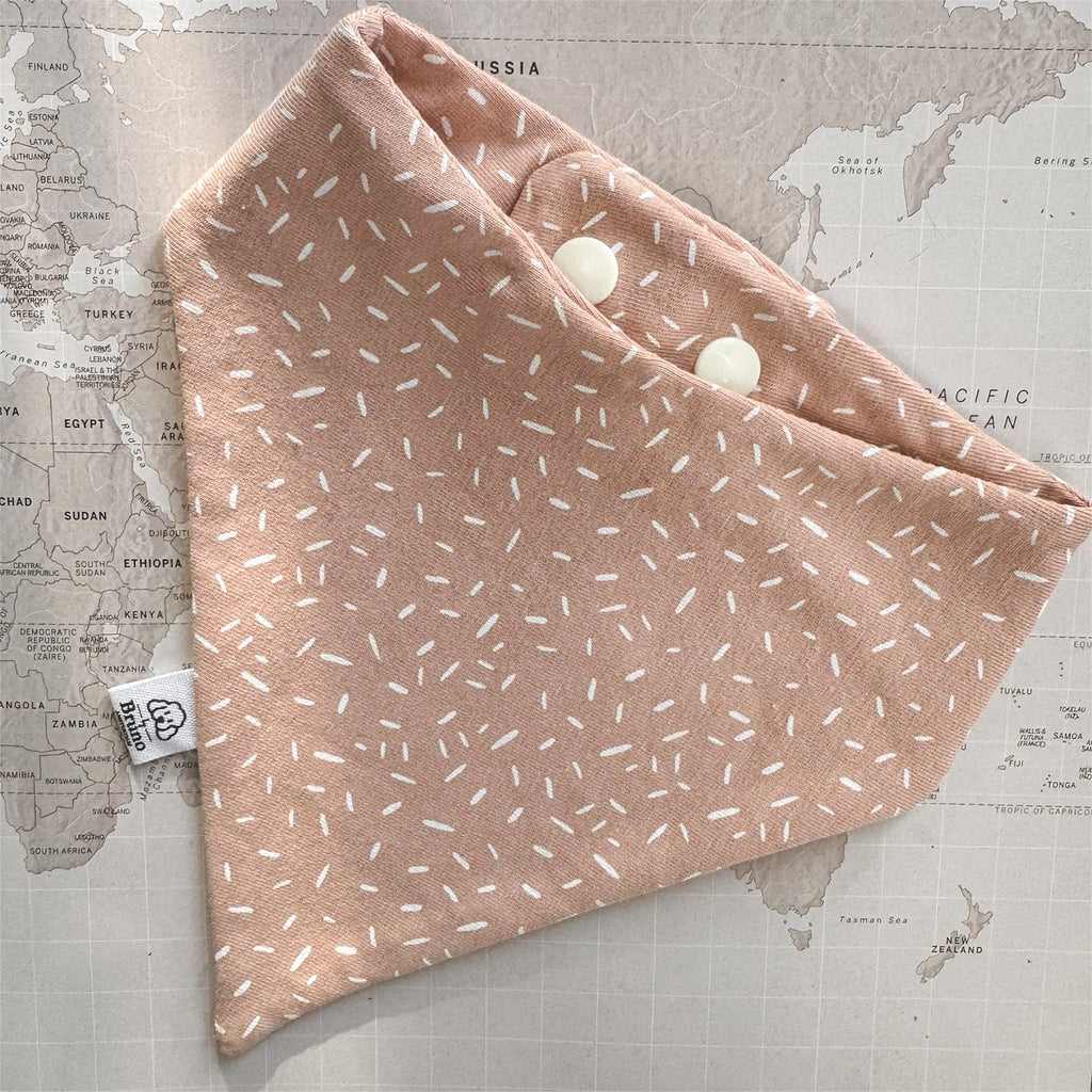 Warm apricot dog bandana with a soft, tonal scattered pattern on a world map background.