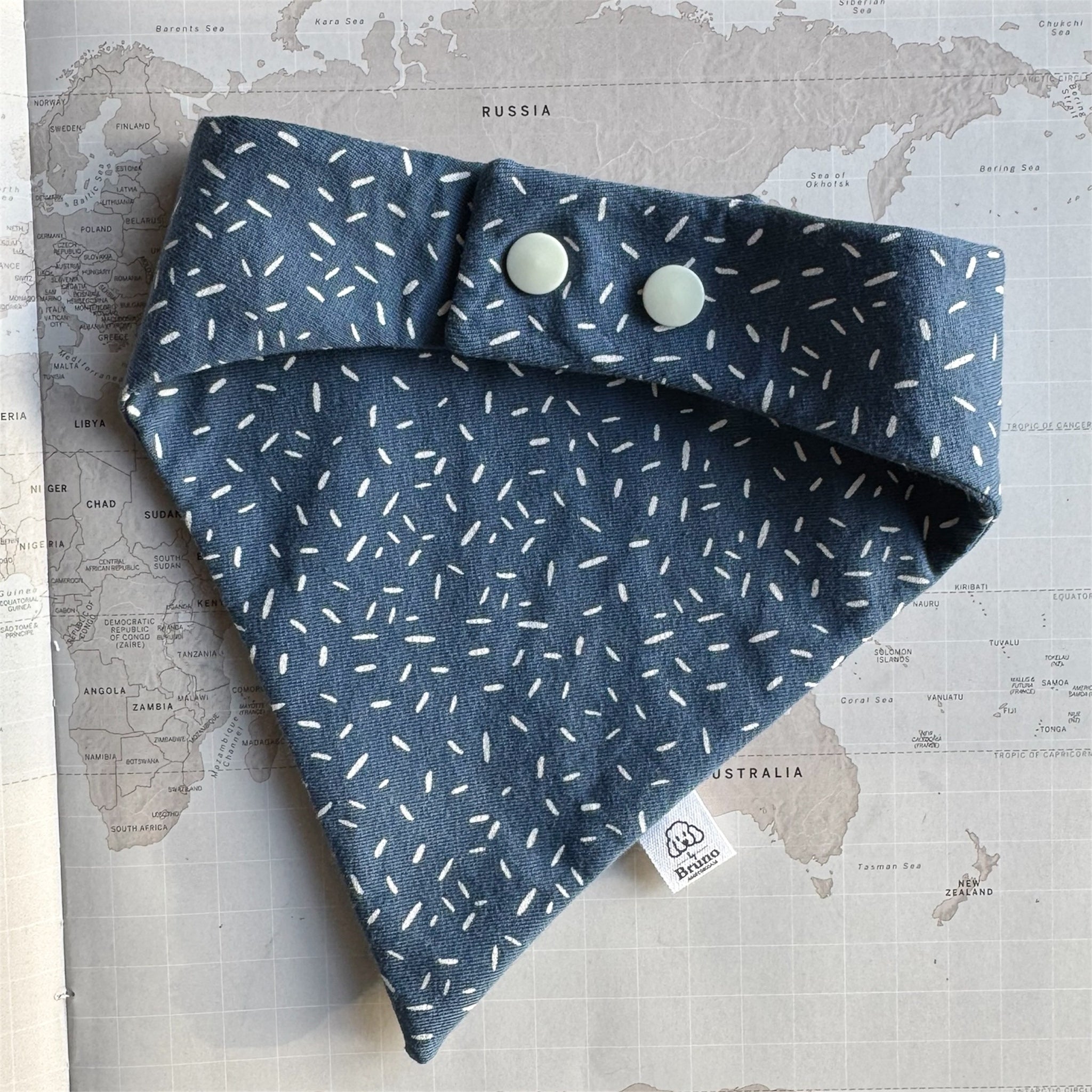 Back side of deep dusty blue dog bandana scattered with fine white sprinkles and with pearl coloured buttons.