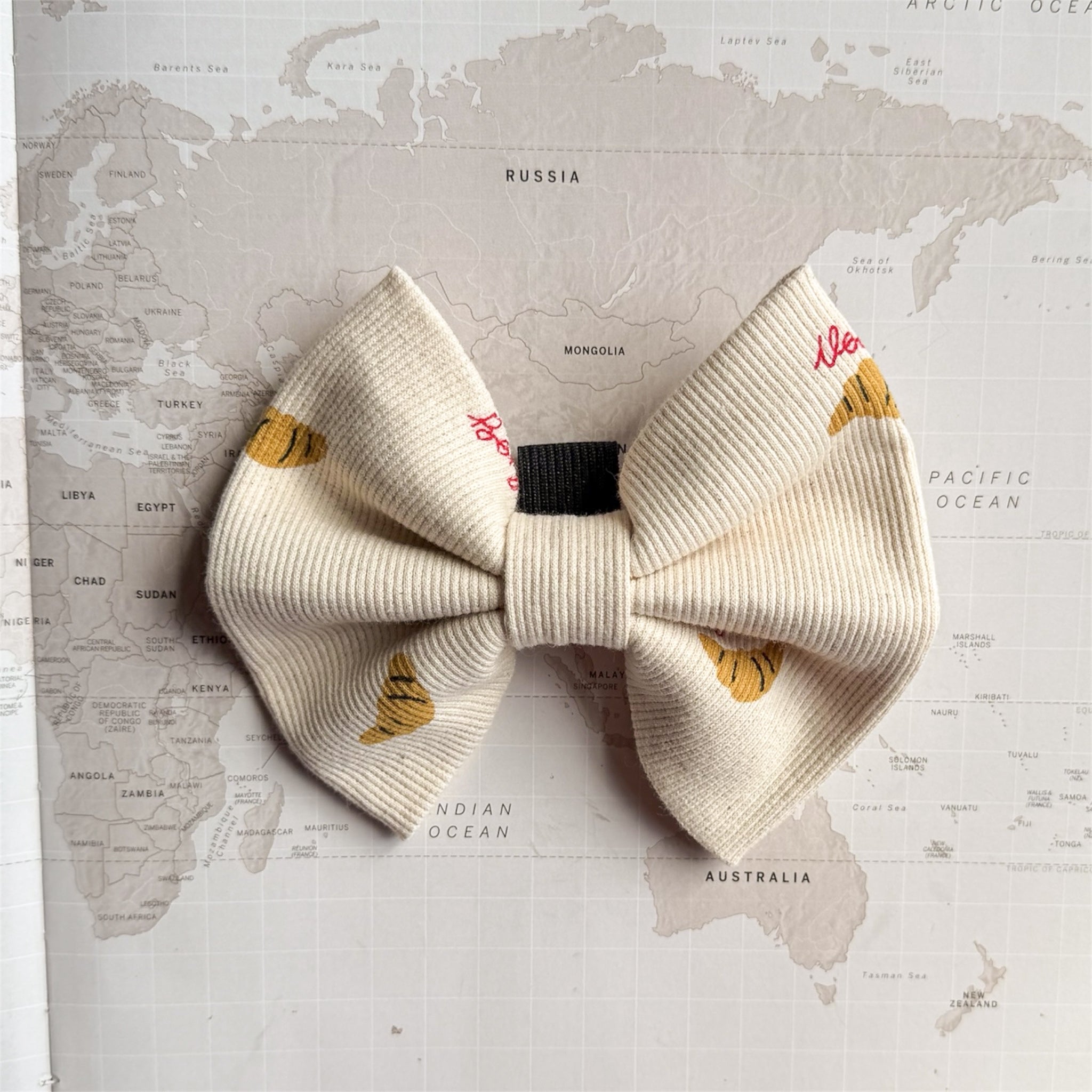 Dog bow with brown croissants and red words in French.