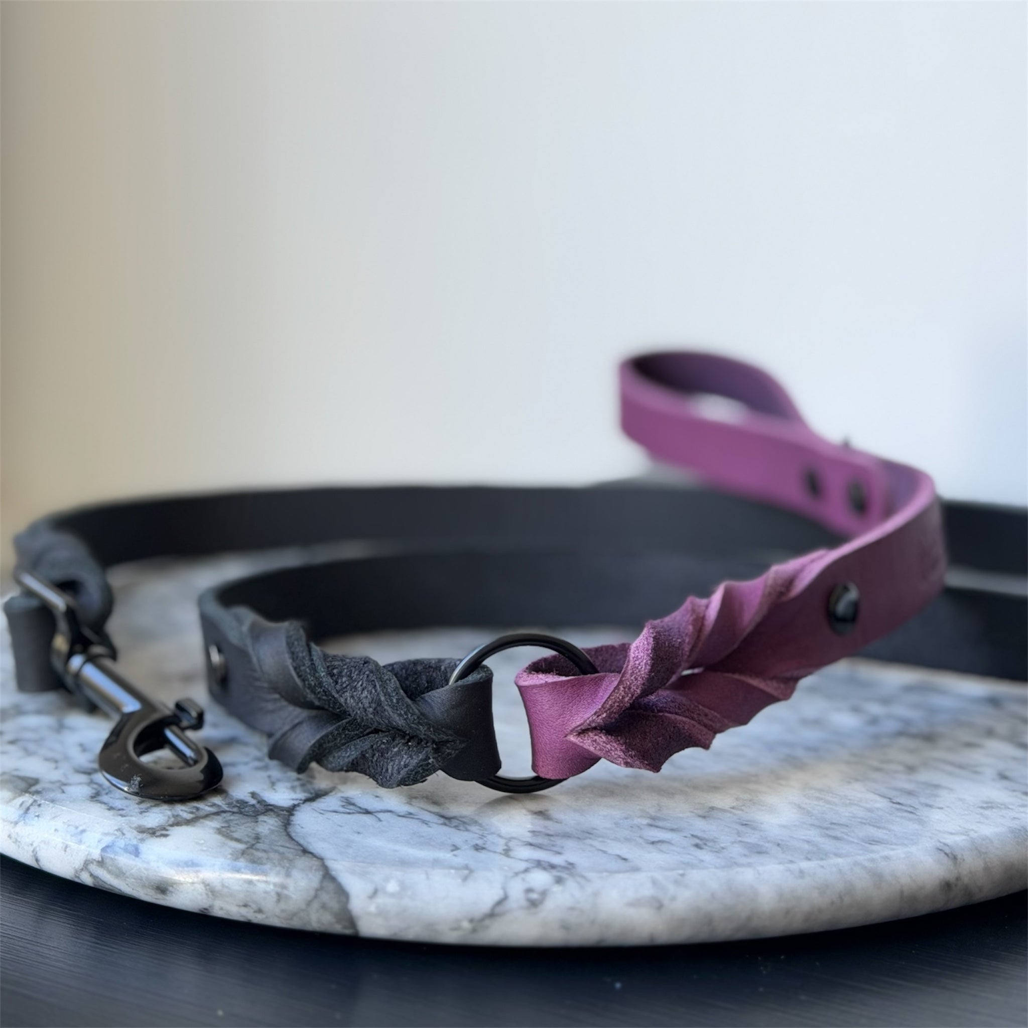 Handmade leather dog leash in purple and black on a map background.