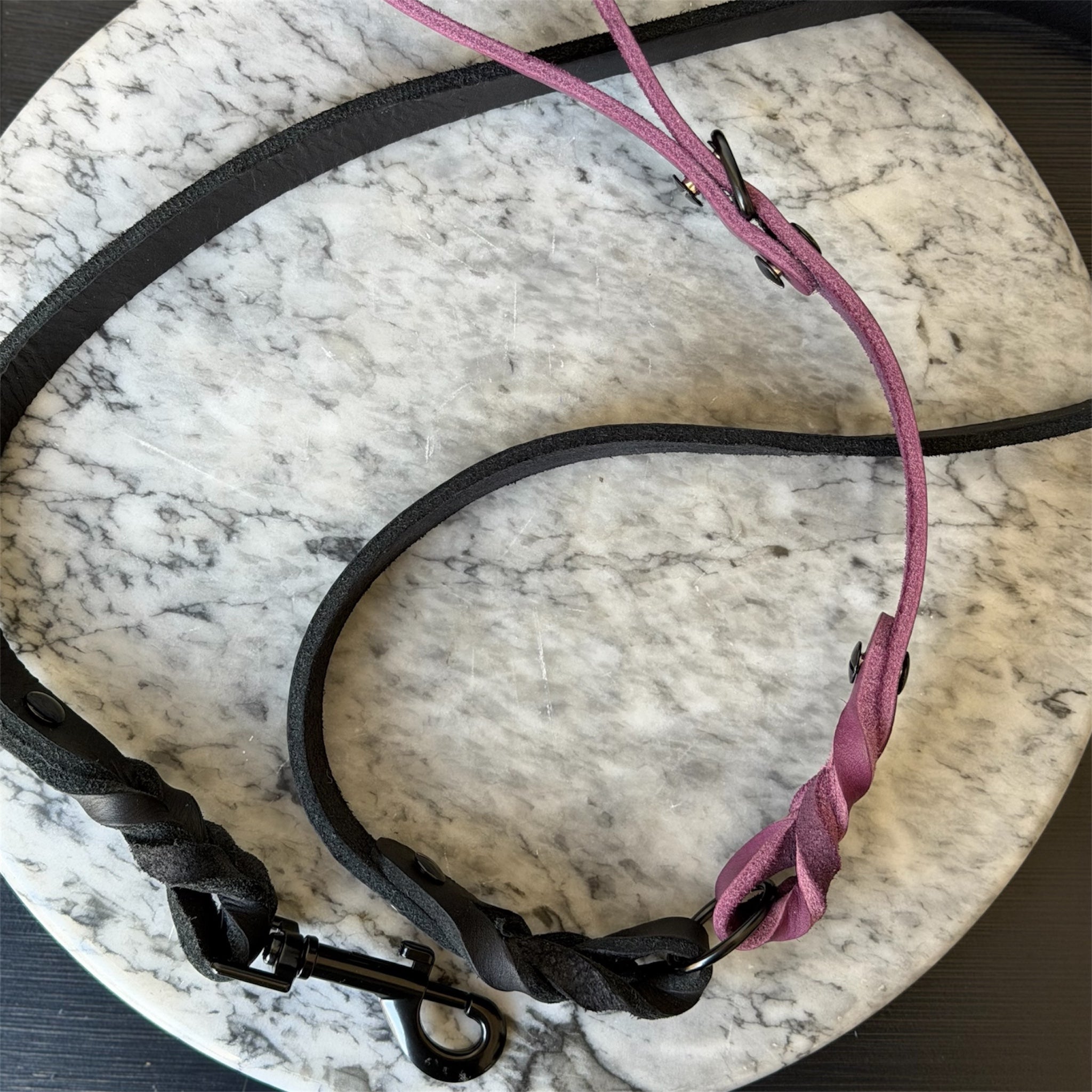 Handmade leather dog leash in purple and black on a map background.