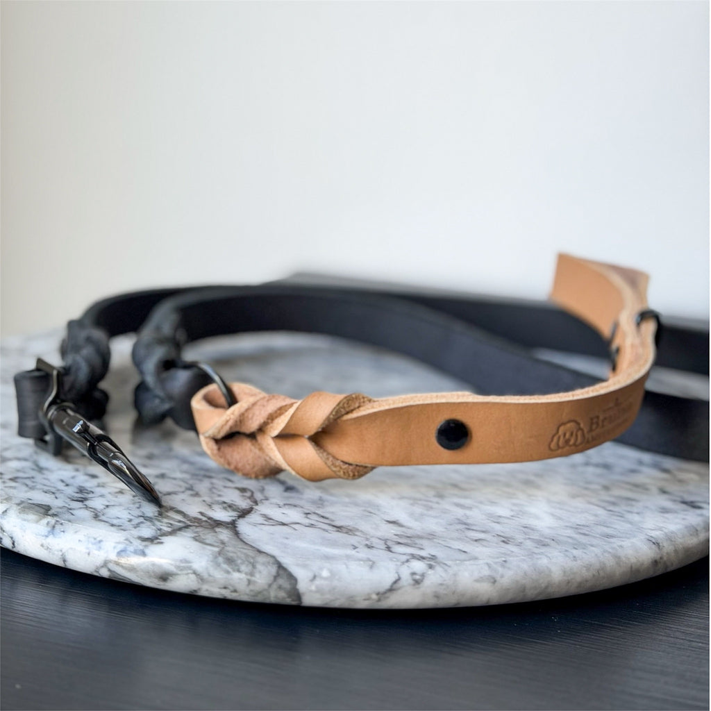 Camel leather dog leash with black hardware on a marble surface.