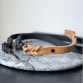 Camel leather dog leash with black hardware on a marble surface.