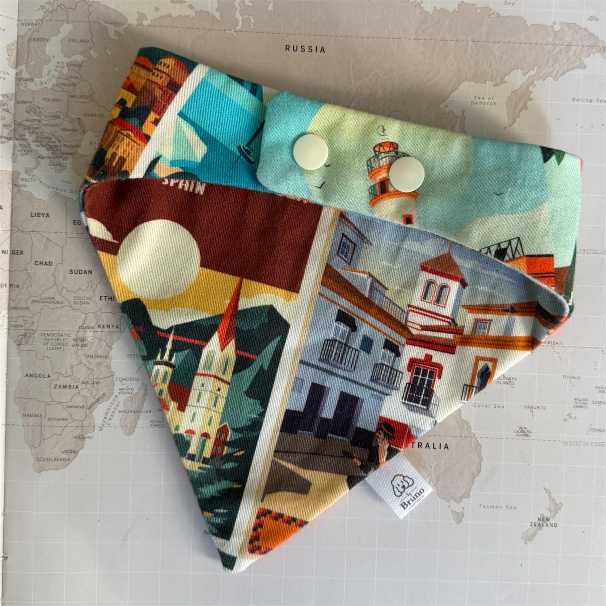 Back side of the Postcards from Spain bandana with plastic buttons on a map background.