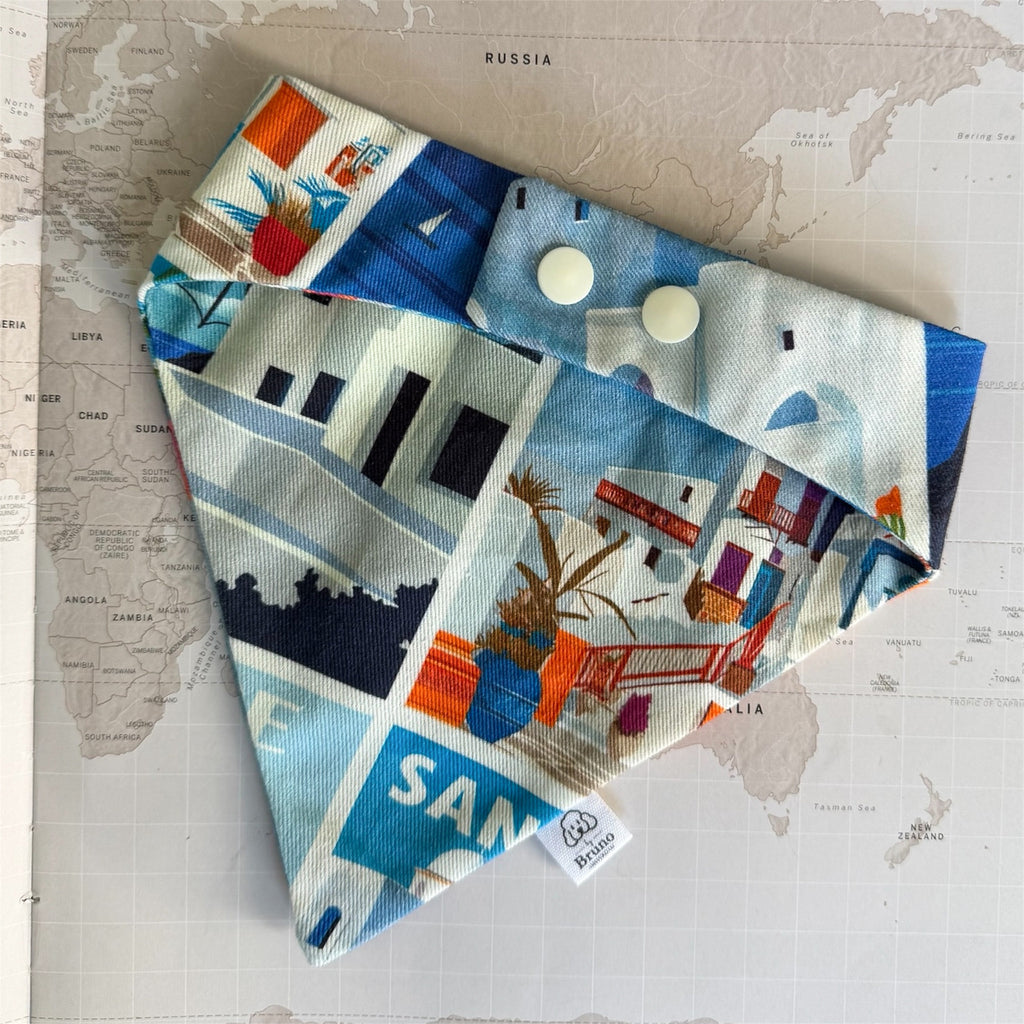 Back side of a colorful bandana with Greek city-themed designs and plastic buttons  on a map background.