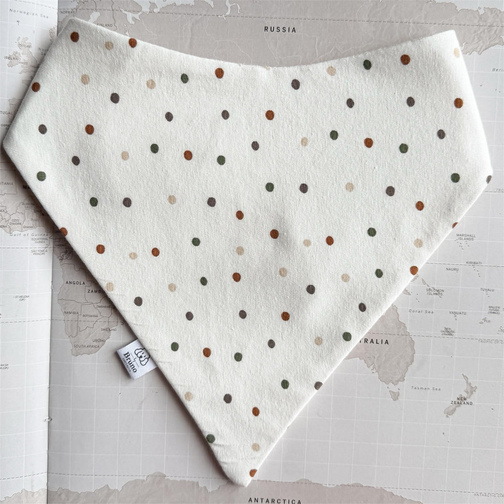 White dog bandana with green and rusted dots on a world map background.