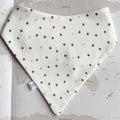 White dog bandana with green and rusted dots on a world map background.