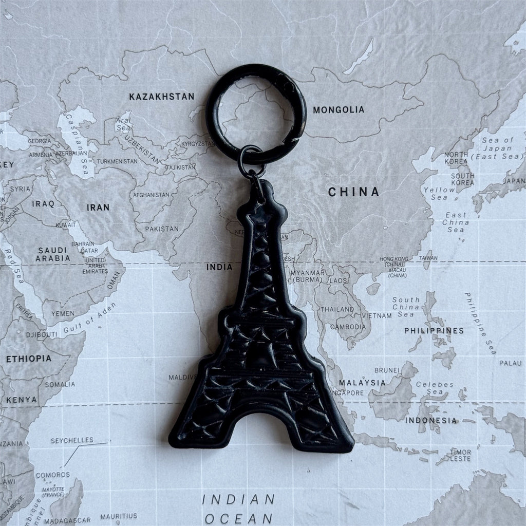 Eiffel Tower dog tag size L on a world map surface.