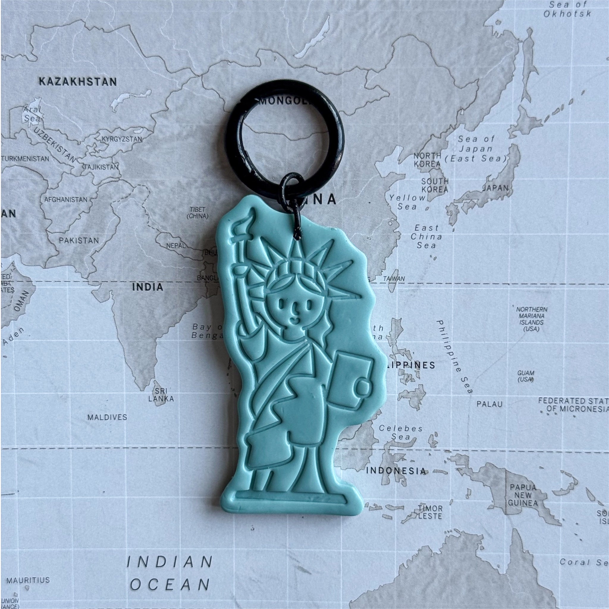 Statue of Liberty dog tag on a world map surface, size L.