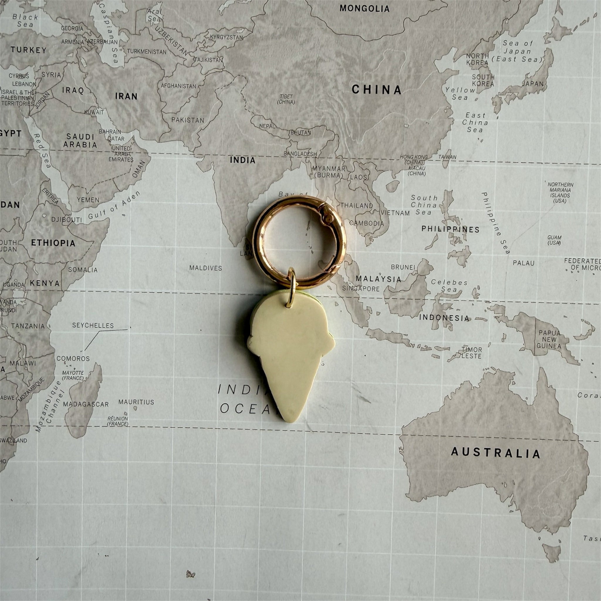 Back side of the custom pastel pink polymer clay dog tag with gelato design on a world map background.
