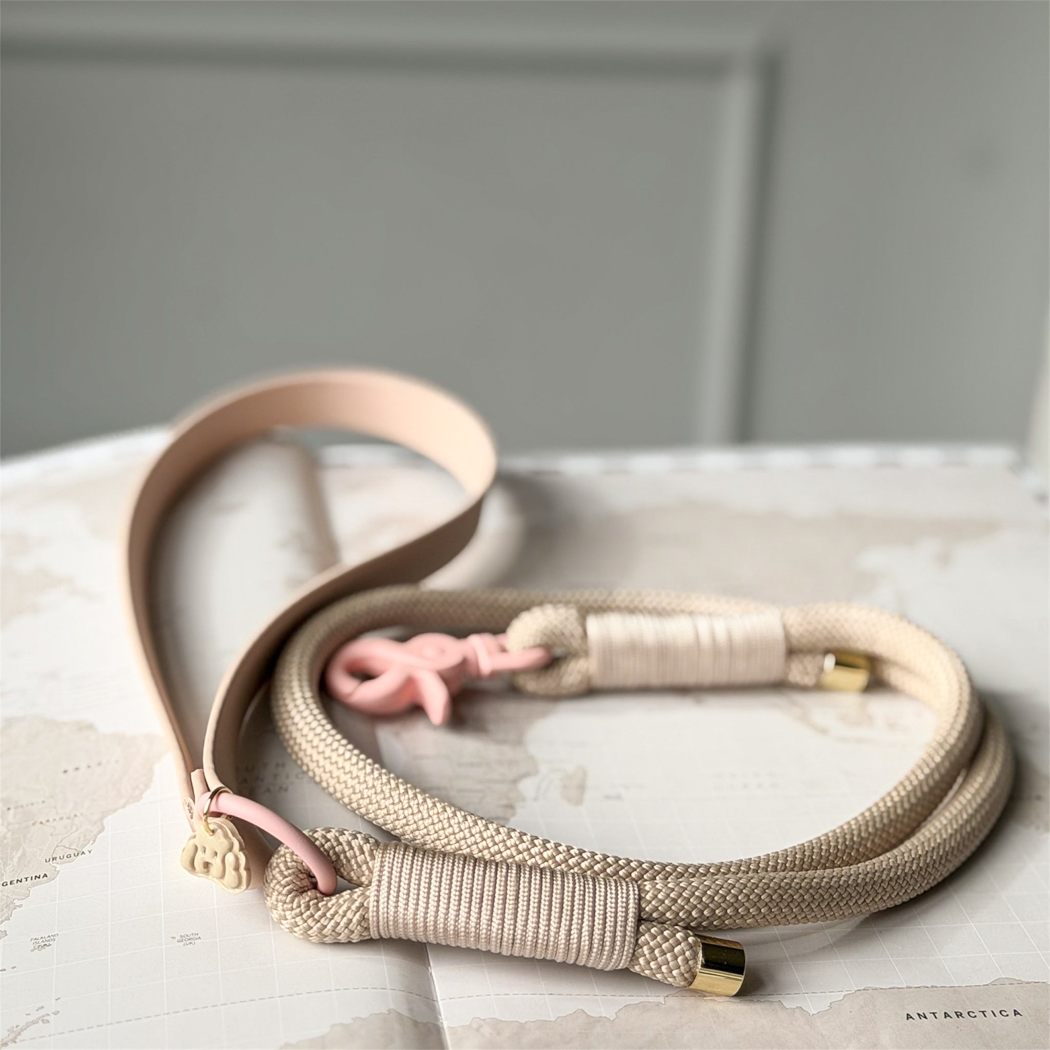 Beige dog leash with pink and gold accents on a marble surface
