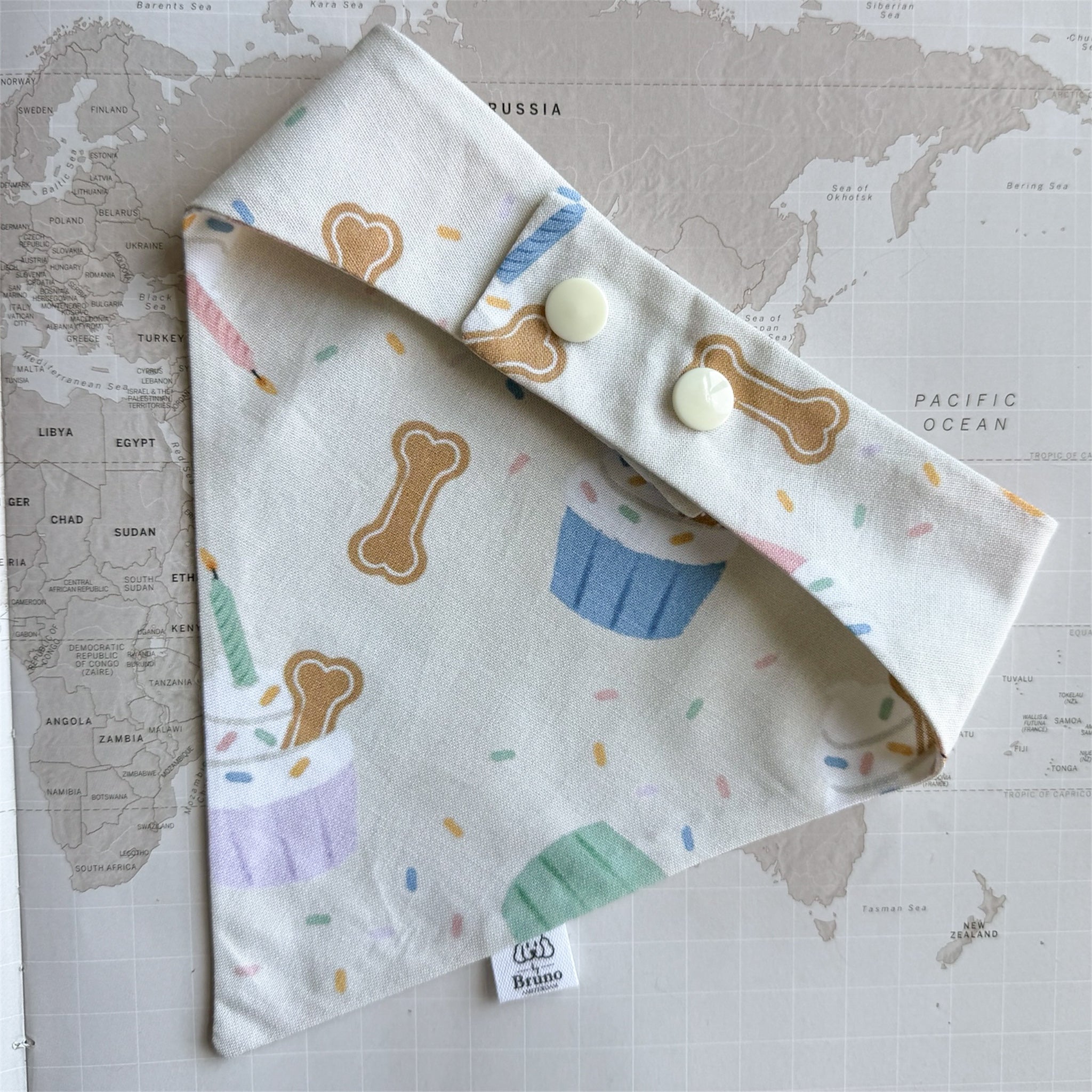 Back view of the handmade Birthday Party dog bandana with adjustable snap closure and festive cupcake, biscuit and sprinkle print.