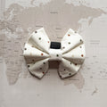 White dog bow with brown and green polka dots on a world map background.