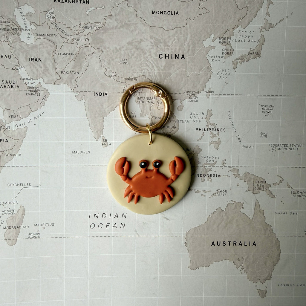 Lightweight handmade dog tag featuring a red crab on a world map background.
