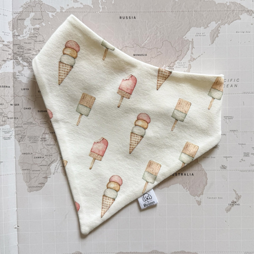 Handmade beige dog bandanna with pastel ice creams on a world map background.
