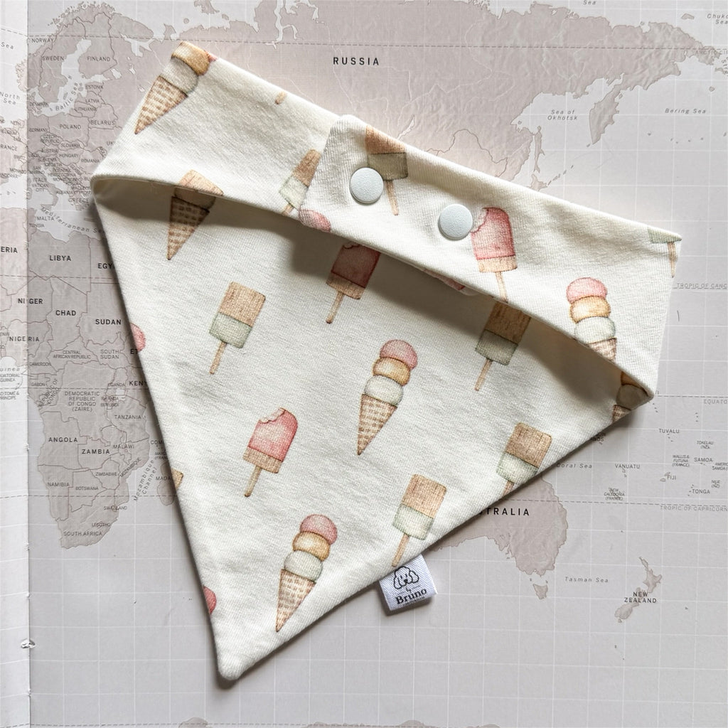 Back side of the handmade beige dog bandanna with pastel ice creams on a world map background.