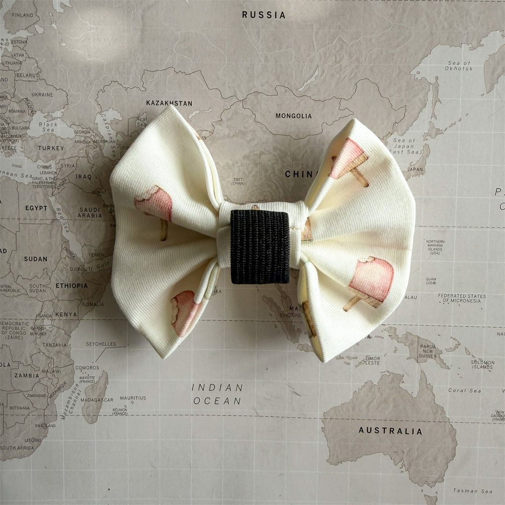 Back side of the lightweight dog bow inspired by Italian gelato and summer pastels with the elastic loop on a world map background.