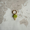 Custom pastel green polymer clay dog tag with gelato design on a world map background.