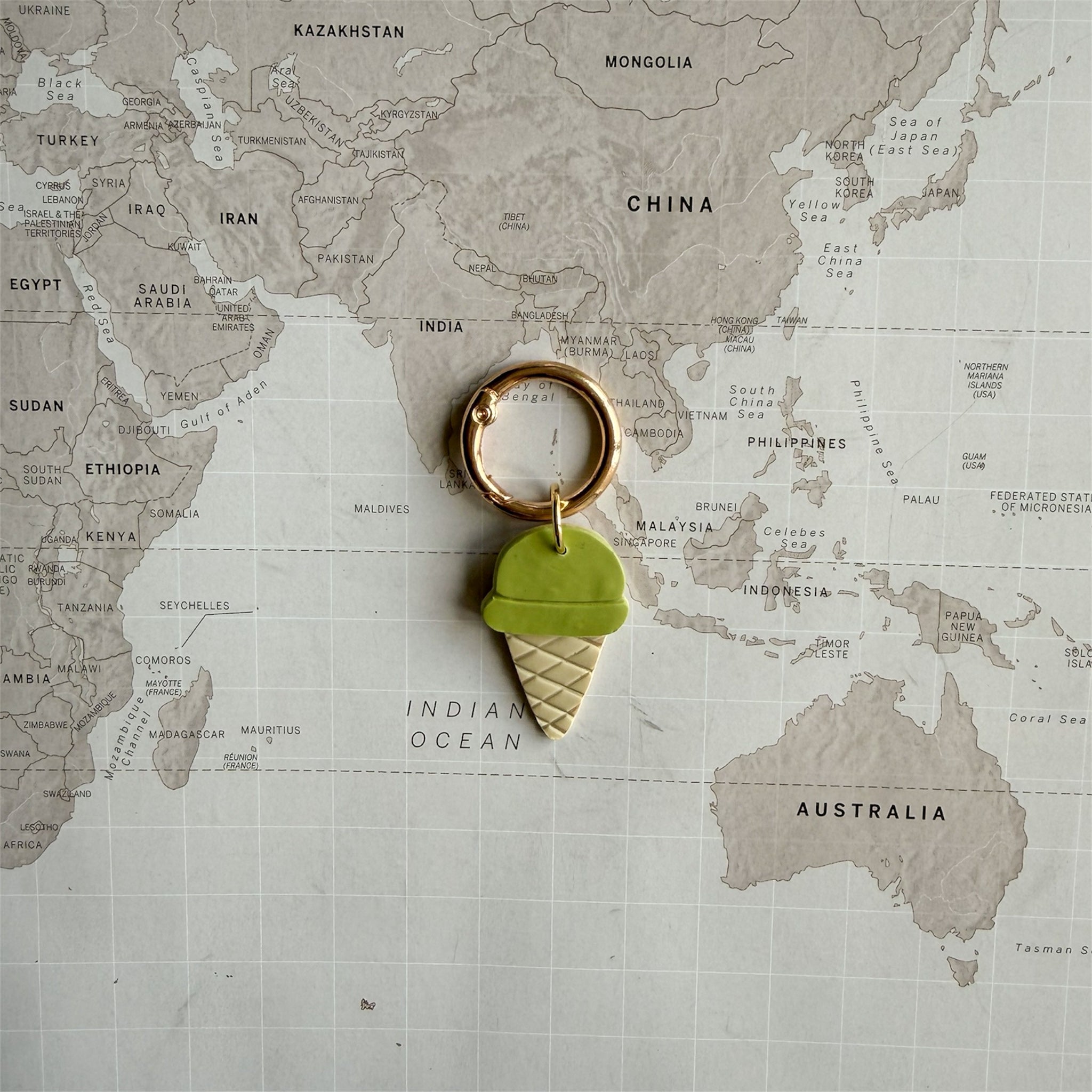 Custom pastel green polymer clay dog tag with gelato design on a world map background.