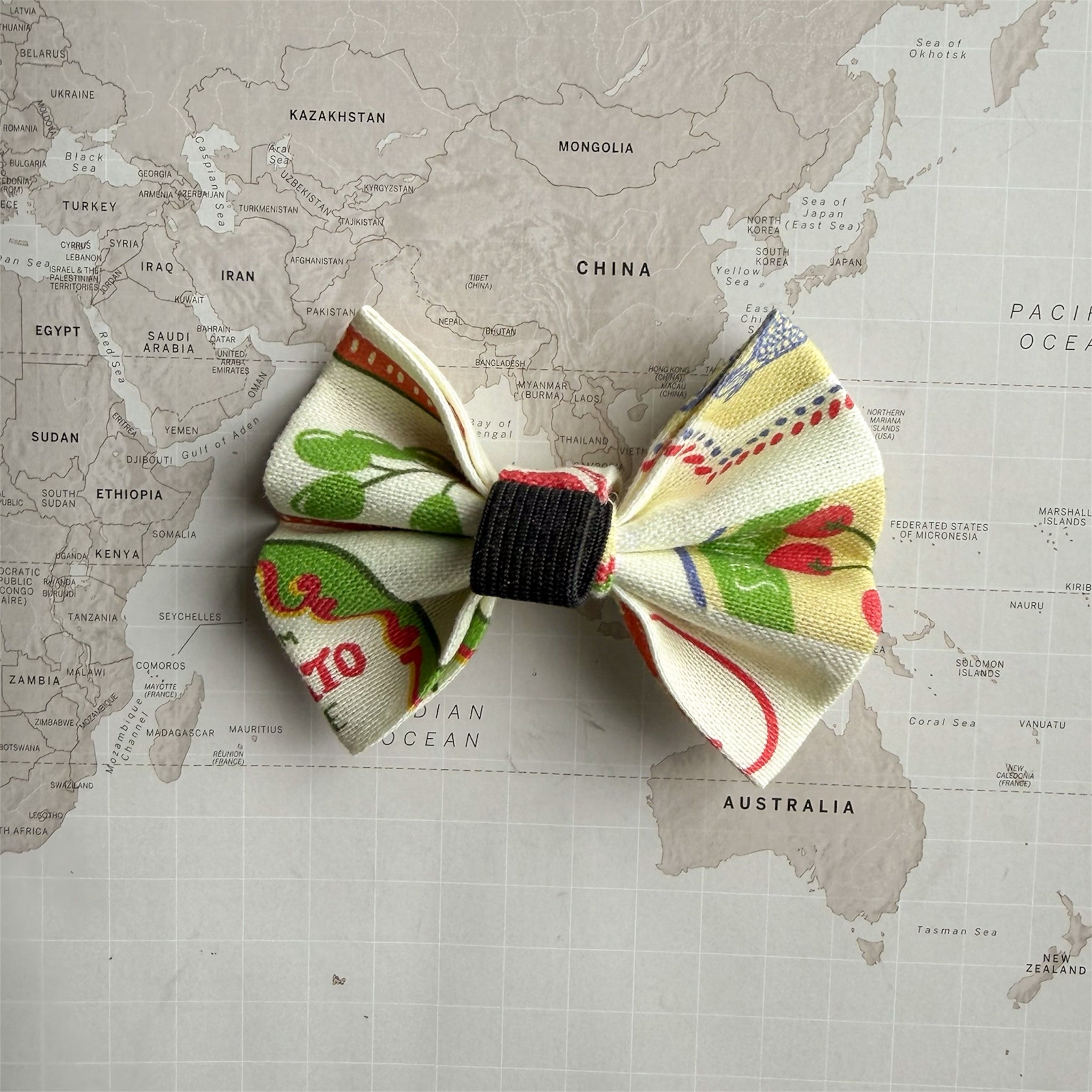 Back side of the Ristorante al Mare dog bow with elastic loop on a black collar on a world map background.