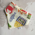 Ristorante al mare dog bandana with fish, crab and pasta on a world map background.