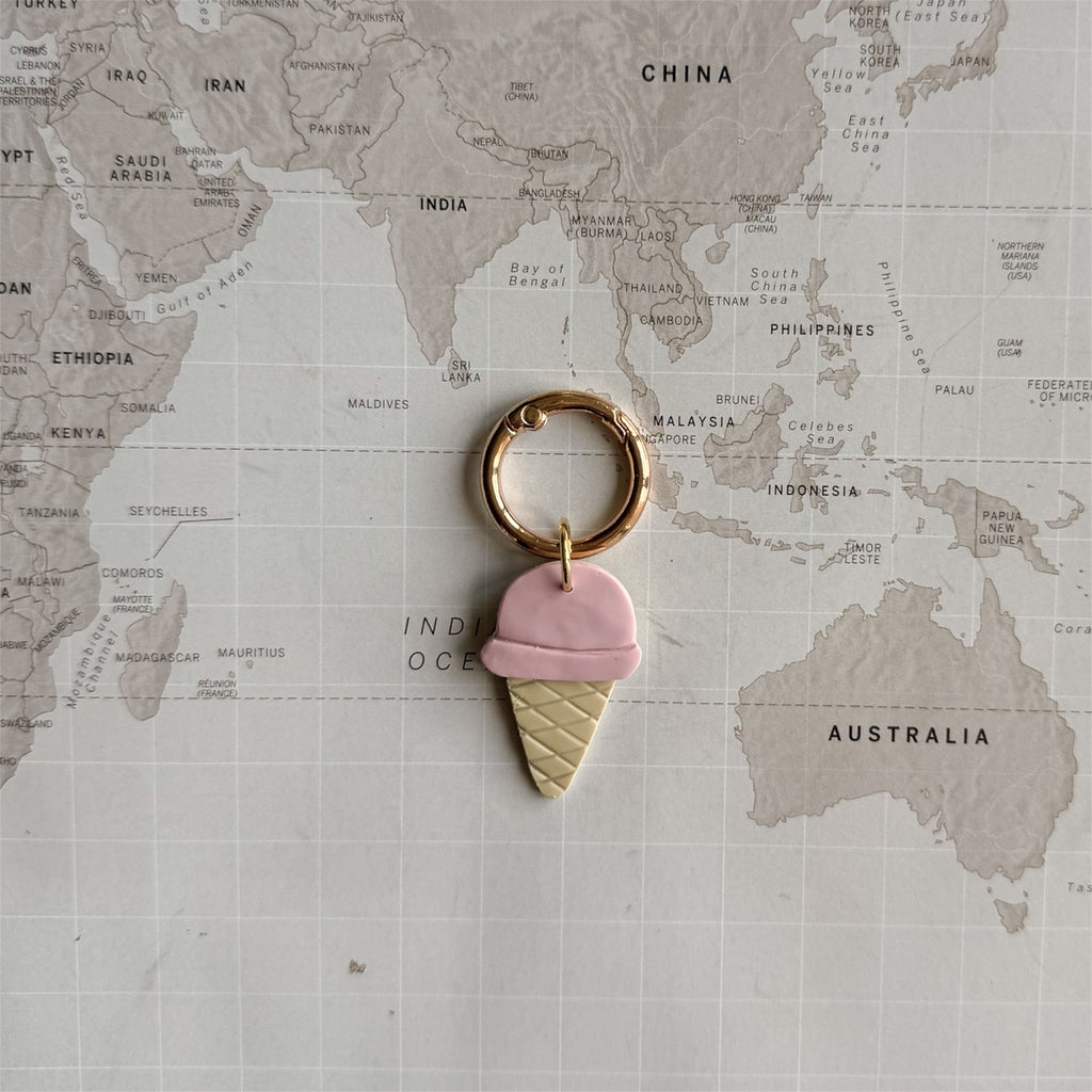 Custom pastel pink polymer clay dog tag with gelato design on a world map background.